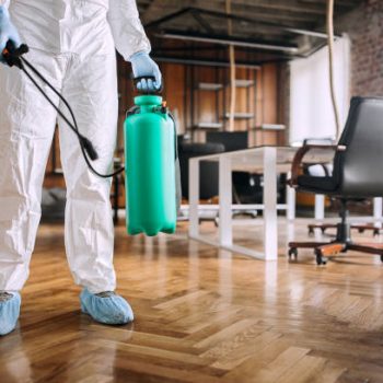 Man in protective suit spraying for disinfection in the office